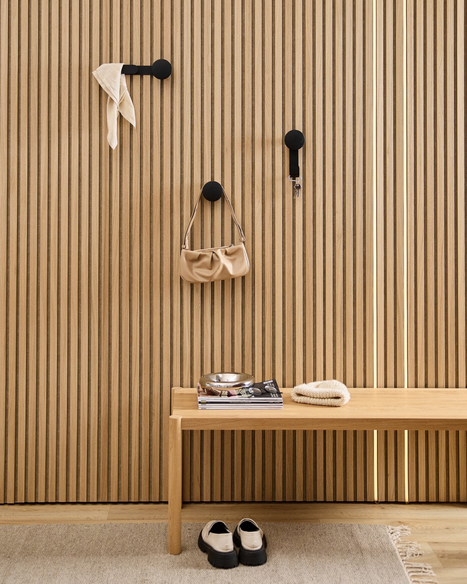 Recibidor minimalista con un perchero WoodUpp Linn Horizontal en Black Oak, con ganchos black, banco de madera, zapatos, libros y un plato. Estilo nórdico.